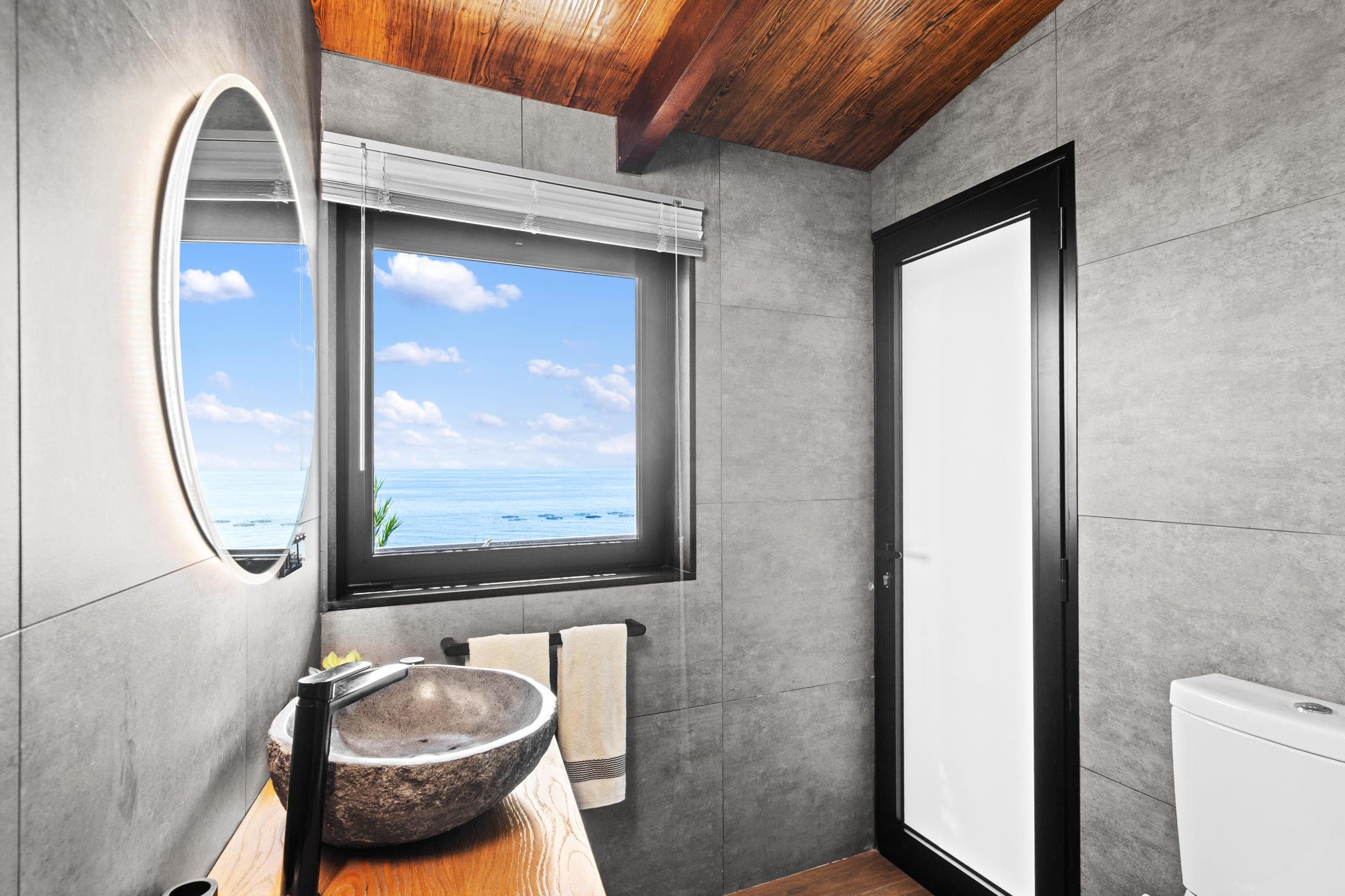 Bathroom mirror and window both framing the same ocean view.