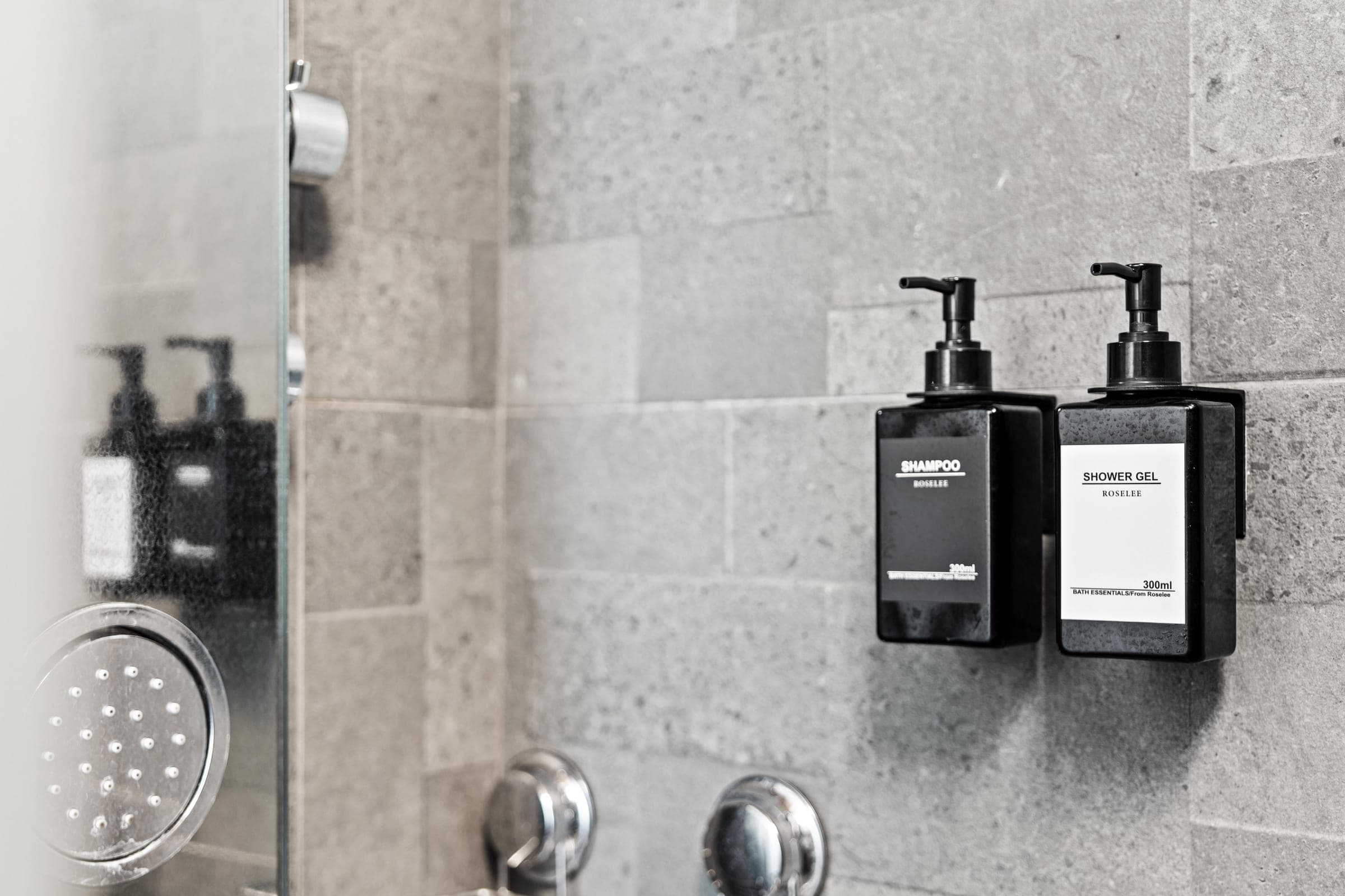 Bath essentials on grey stone tile in the walk-in shower.