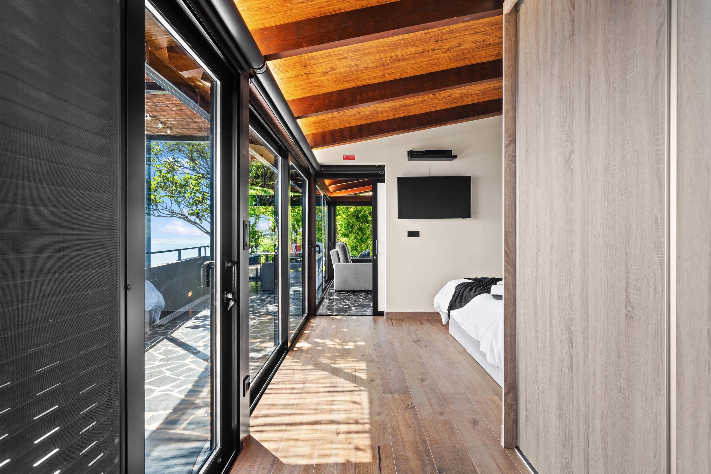 A glass wall slides fully open from the bedroom onto the sea-view terrace.