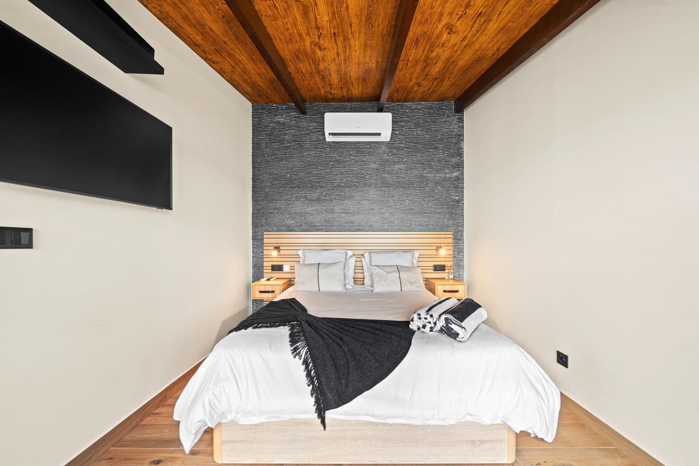 Close view of the bed against the textured stone headboard wall.