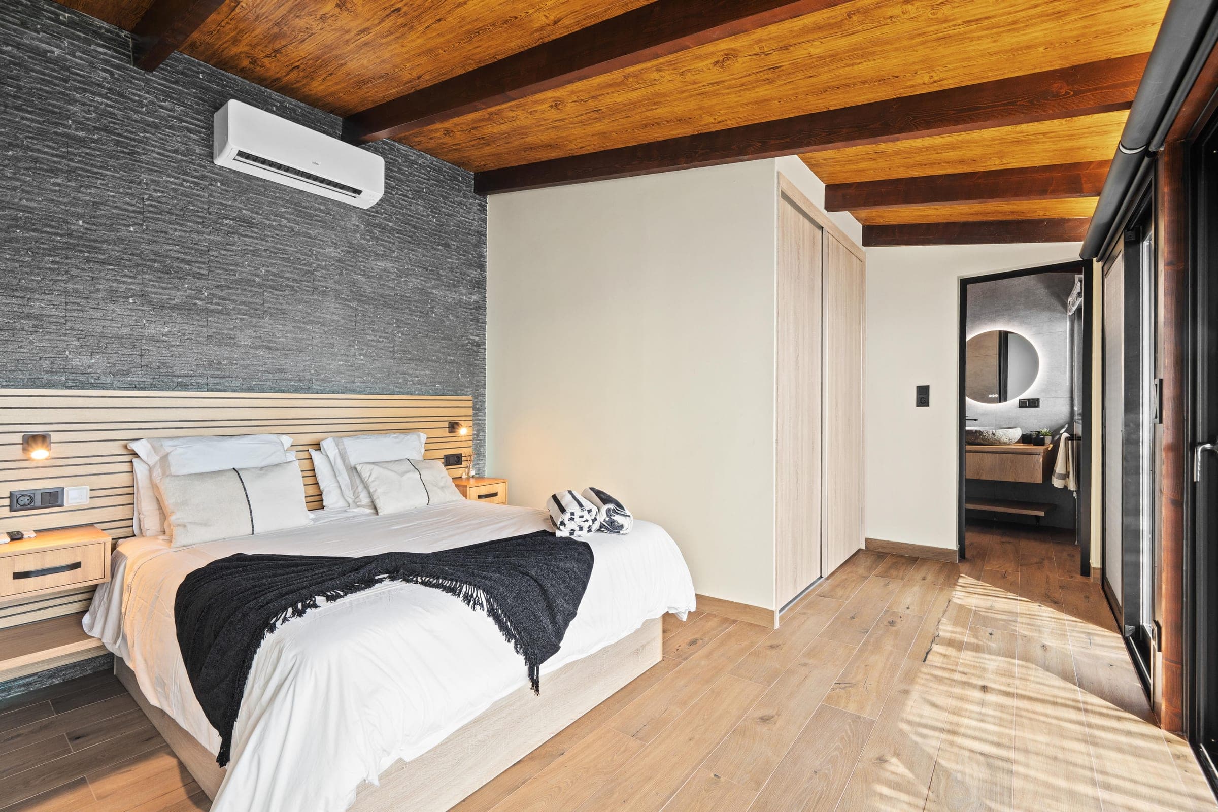 Bedroom with a glimpse through to the ensuite's round mirror.
