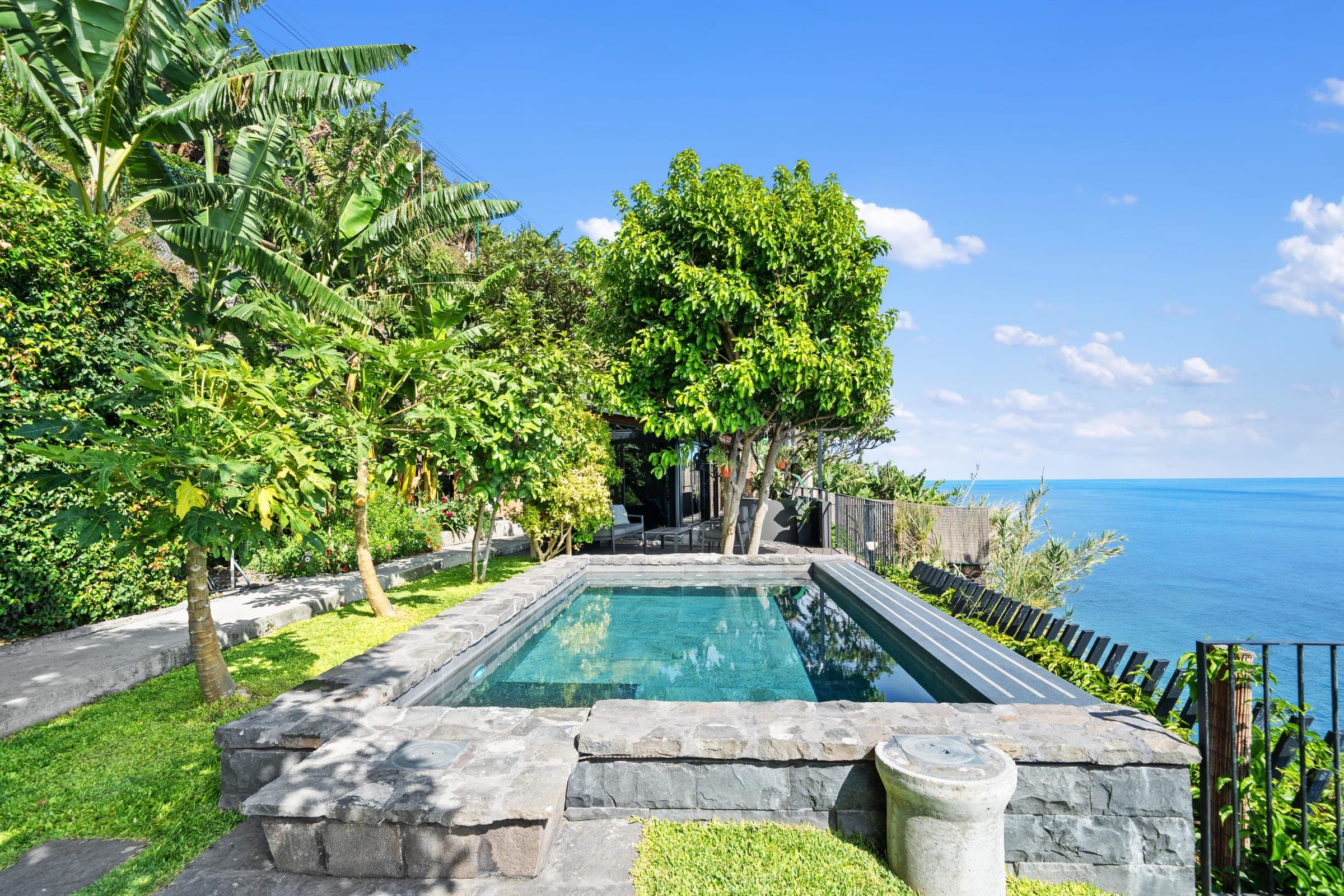 The infinity pool meets the garden, the Atlantic stretching beyond the rail.